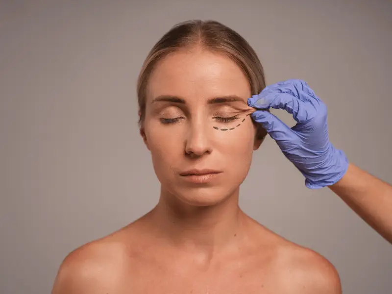 Blefaroplastica e palpebre cadenti: una guida chirurgica completa Un chirurgo esamina le palpebre cadenti durante una visita di consultazione per blefaroplastica presso la Vivid Clinic.