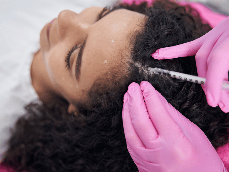 Trasplante capilar para mujeres: 10 consejos tranquilizadores antes de tu transformación. A female patient having her scalp examined by a surgeon during a post transplant checkup at vivid clinic
